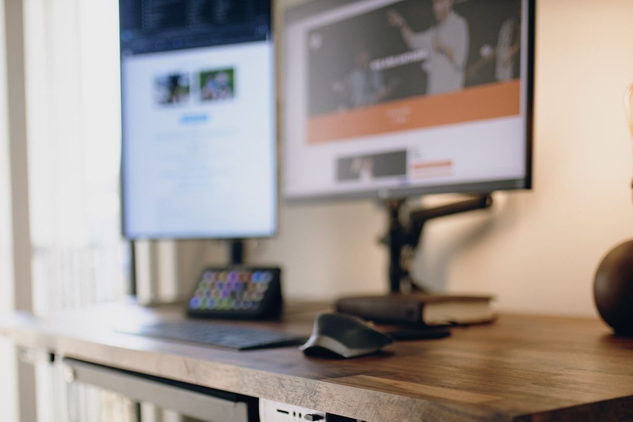 A clean modern home office with a standing desk and monitors